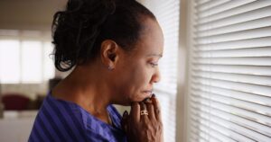 Sad woman looks out window scaled