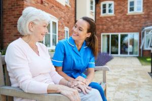 Happy elderly patient sitting with happy nurse